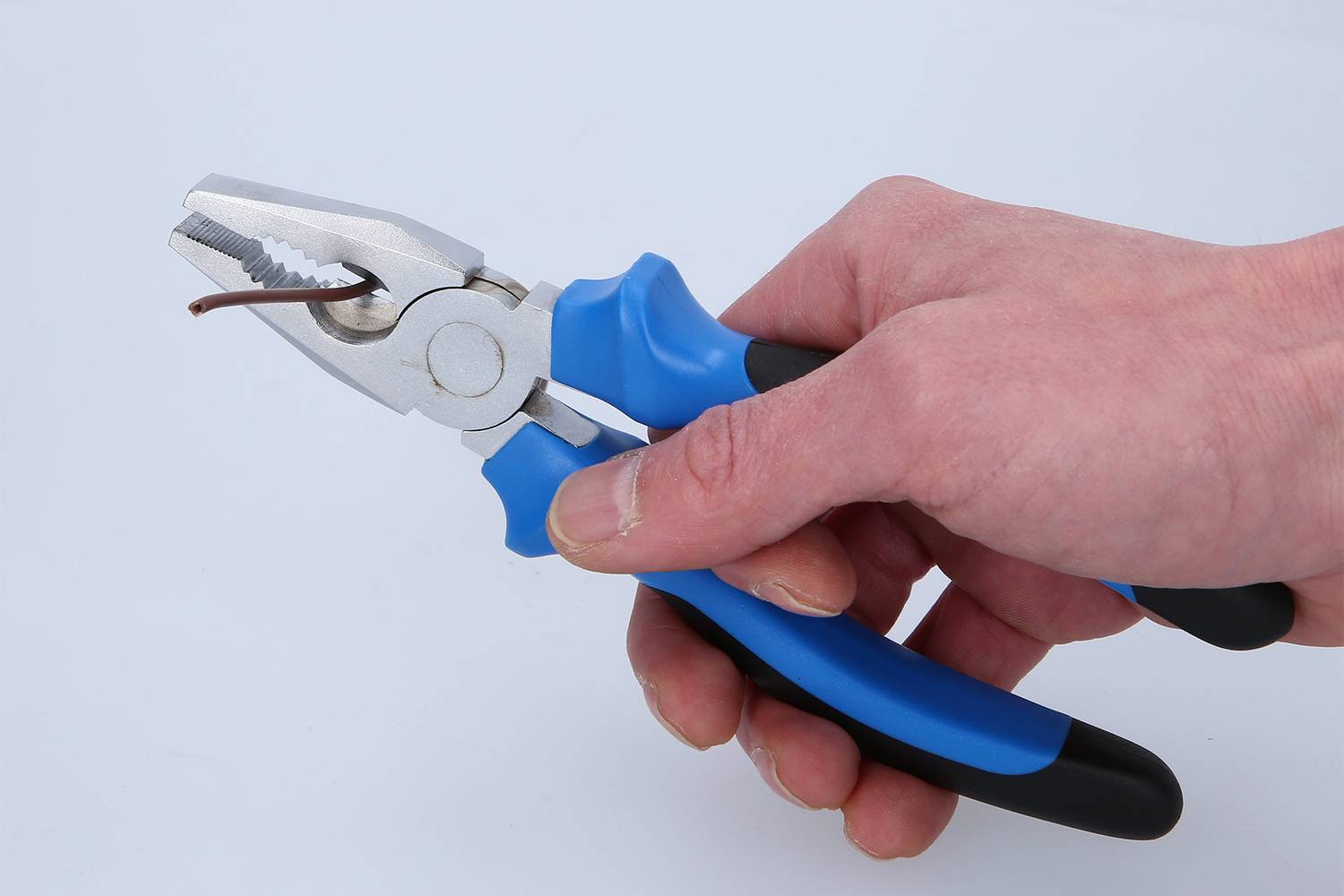 Jedna ruka drží modré kliešte a ohýba nimi tenký drôt.