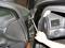 Jedna ruka drží kľúč, ktorý je priložený k pántu na automobiovej bráne.