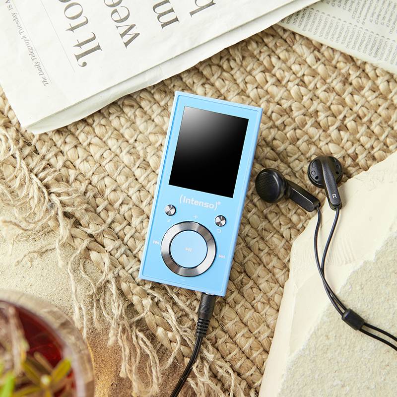 Modrý MP3 prehrávač značky 'Intenso' leží na pletenom povrchu, vedľa neho čierne slúchadlá a zložené noviny.