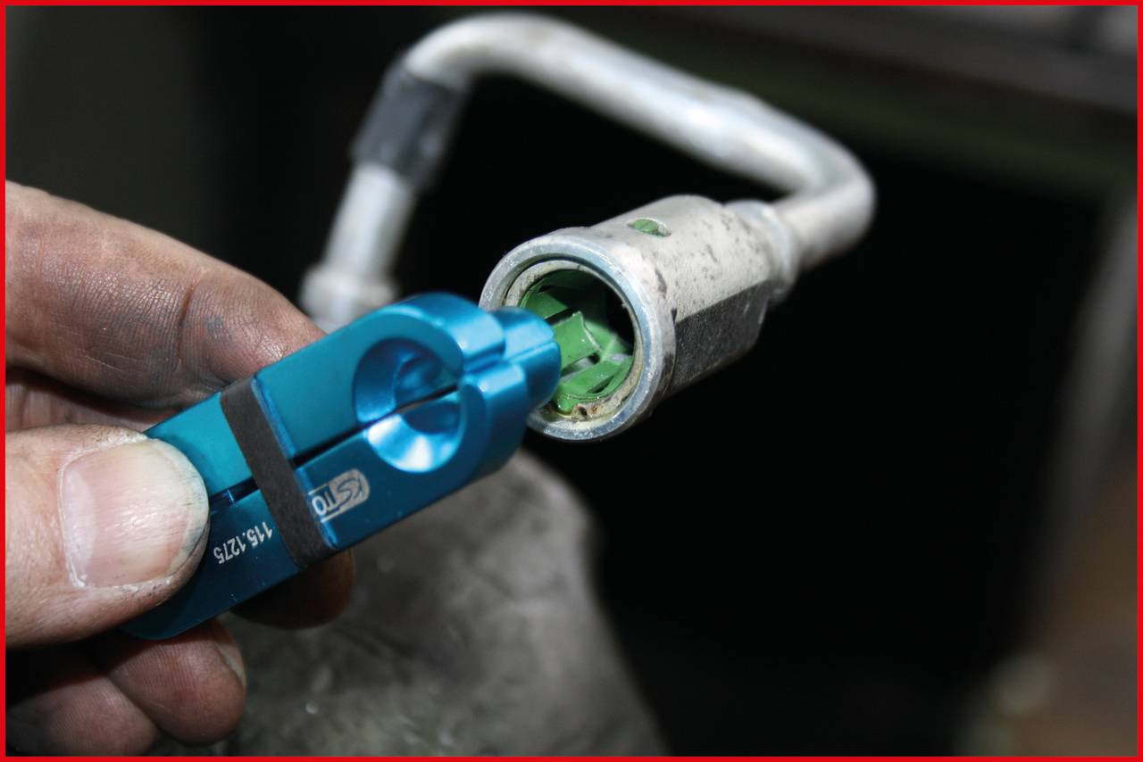 Technický nástroj oddeľuje potrubnú prípojku. Ruka drží modré náradie pri striebornom potrubí so zeleným vstupom.