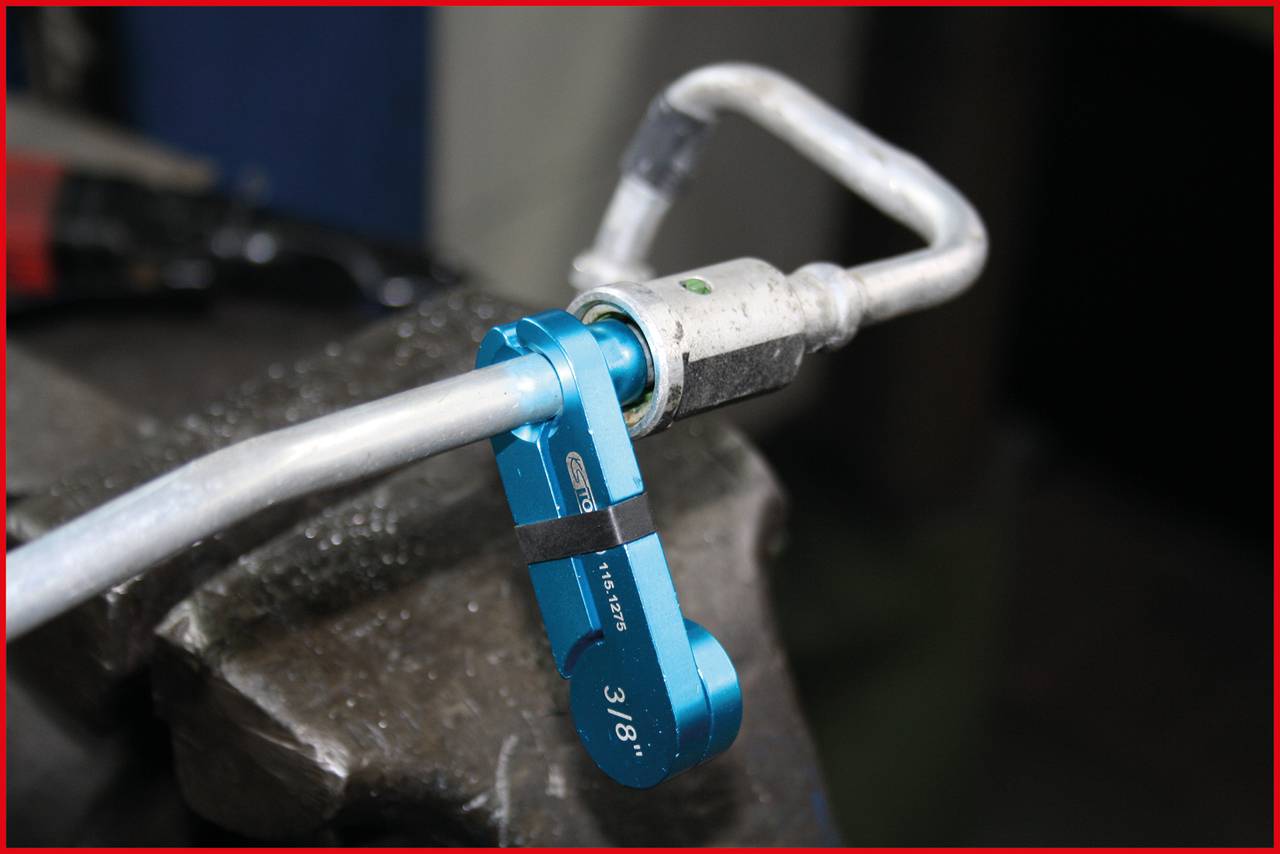 Modrý ohýbač rúr ohýba strieborné kovové potrubie vo zveráku.