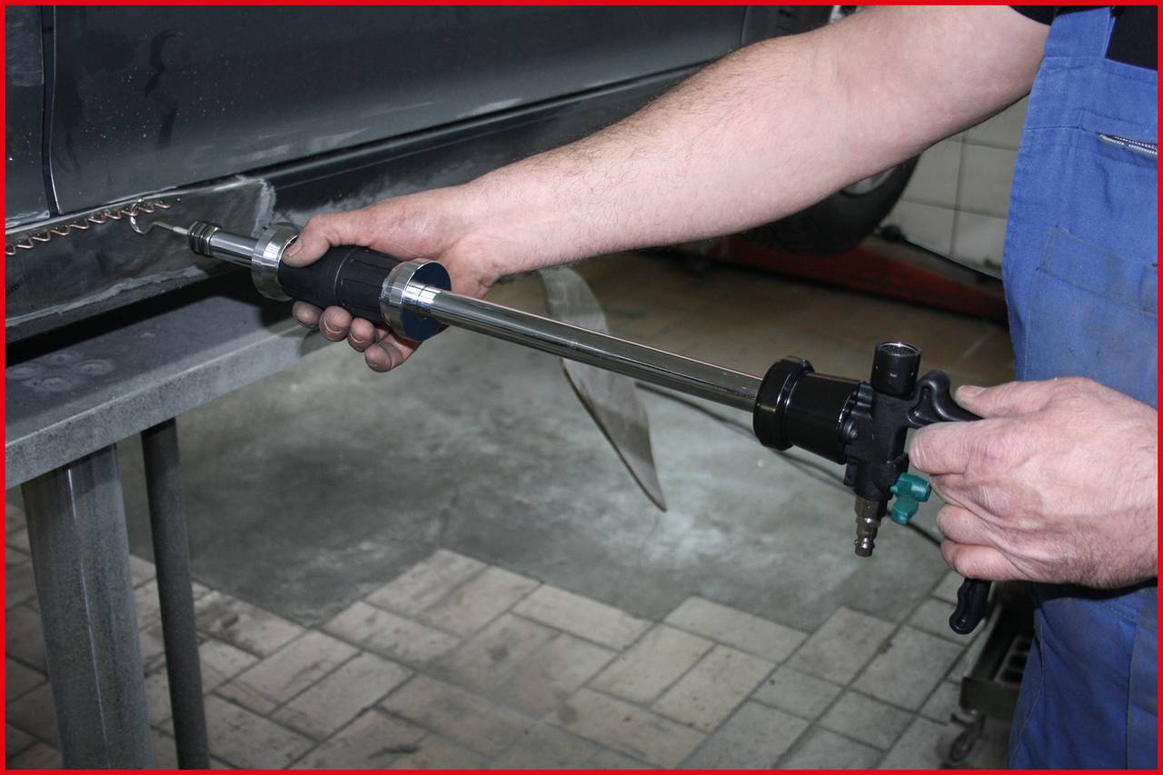 Osoba používa zváracie zariadenie na opravu karosérie automobilu so zameraním na nástroj v ruke.