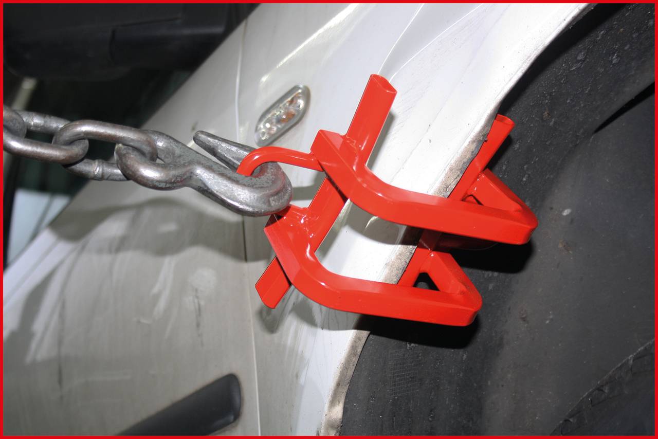 Červený blokovací systém na pneumatike automobilu, ktorý zabraňuje pohybu. Bezpečnostné opatrenie proti neoprávnenému parkovaniu alebo krádeži.