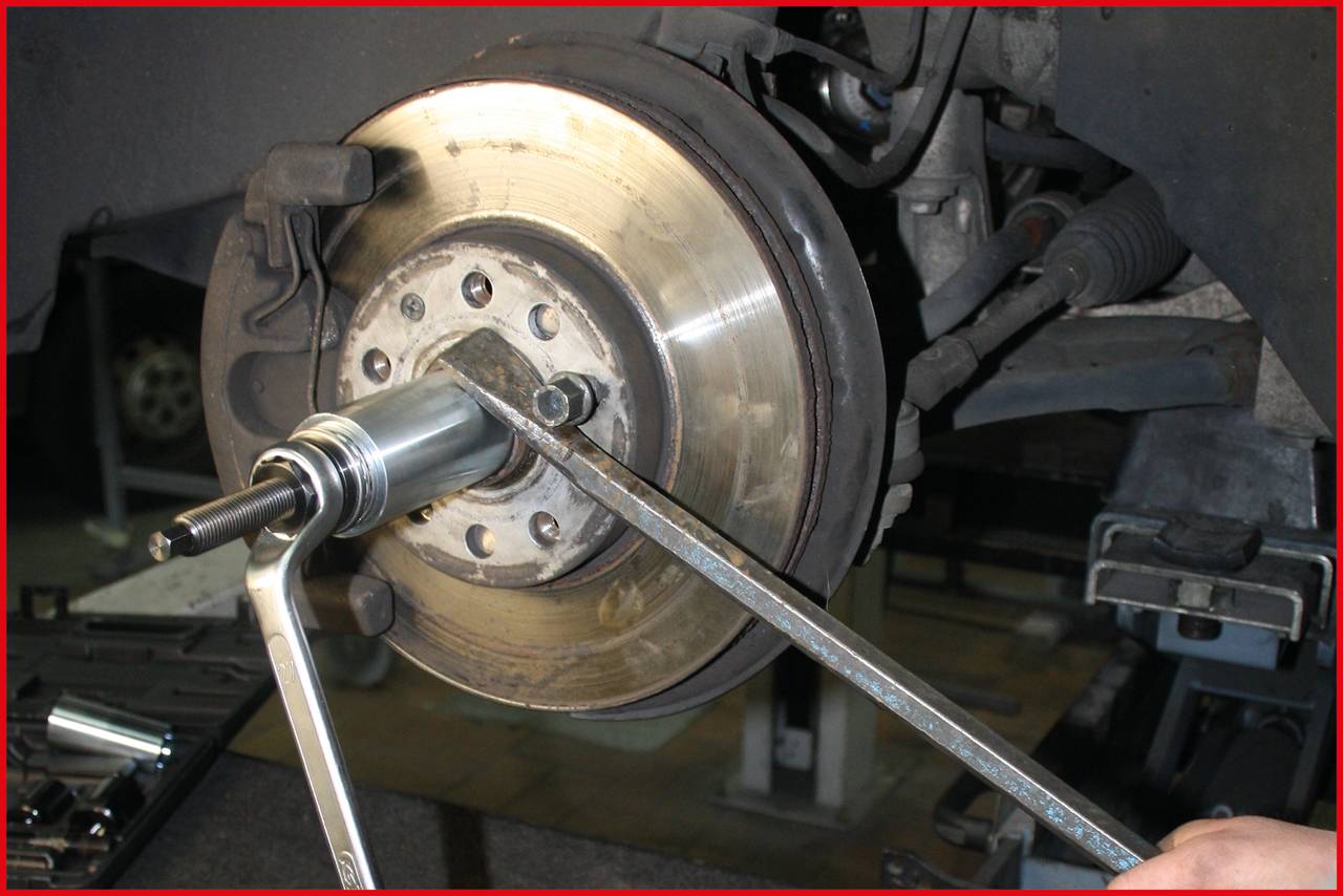 Mechanik montuje brzdový kotúč na automobil. Na obrázku sú viditeľné brzdové komponenty a mechanické náradie určené na opravu.