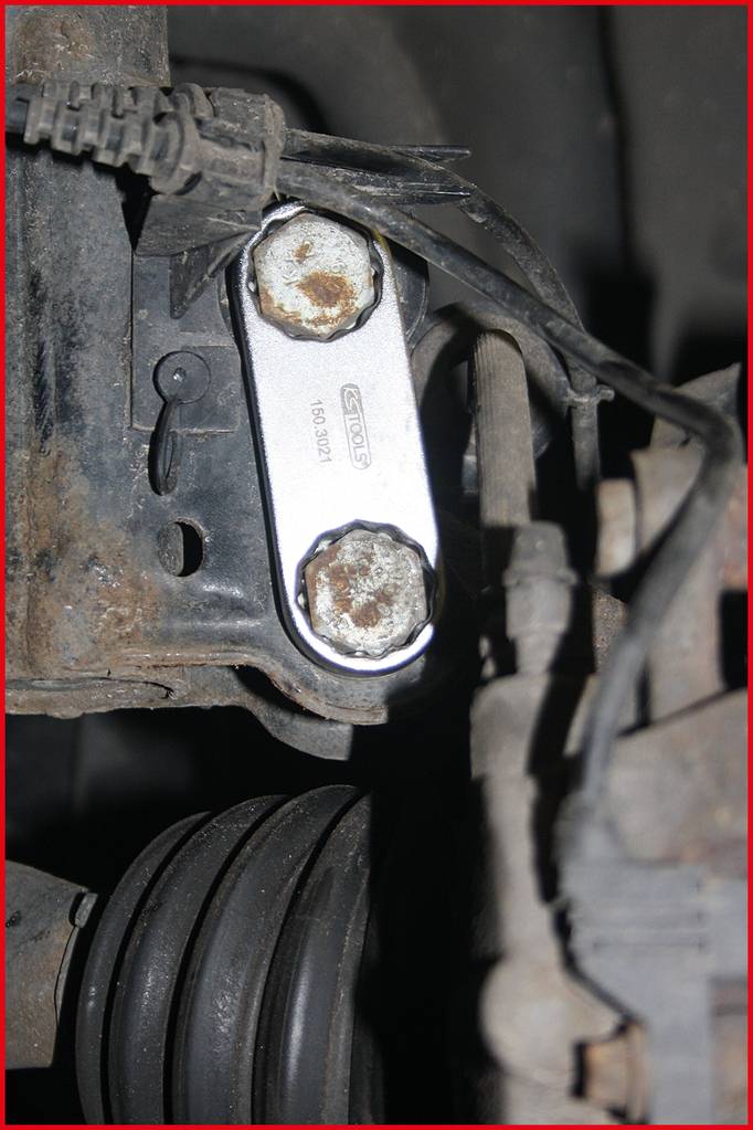 Detailný záber skorodovanej kovovej súčasti v mechanickom zariadení, obklopenej káblami a hadicami.