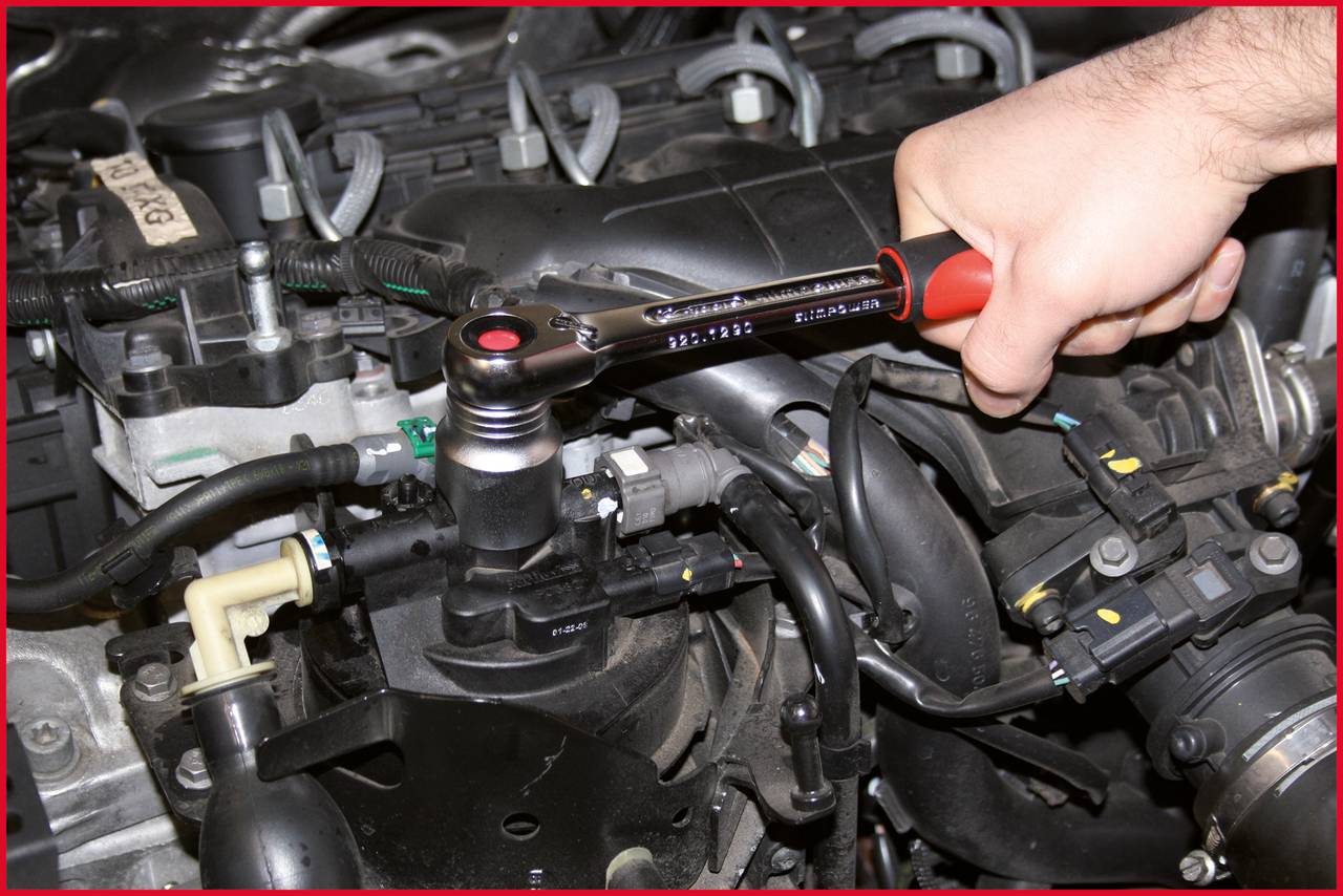 Jedna ruka používa momentový kľúč na dotiahnutie skrutky v motorovom priestore automobilu.