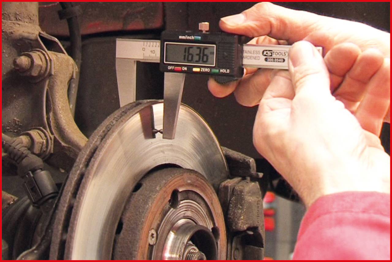 Mechanik meria hrúbku brzdového kotúča digitálnym posuvným meradlom. Na displeji je zobrazená hodnota '16,36'.