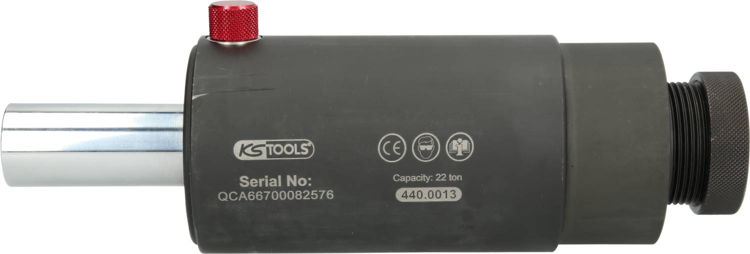 Hydraulický valec od KS Tools so sériových číslom QCA86700082576, s maximálnou kapacitou 22 ton. Čierny valec s červeným tlačidlom.