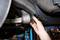 Ruka vykonáva mechanickú kontrolu súčasti automobilu pod vozidlom zdvihnutým na zdvíhacej plošine.