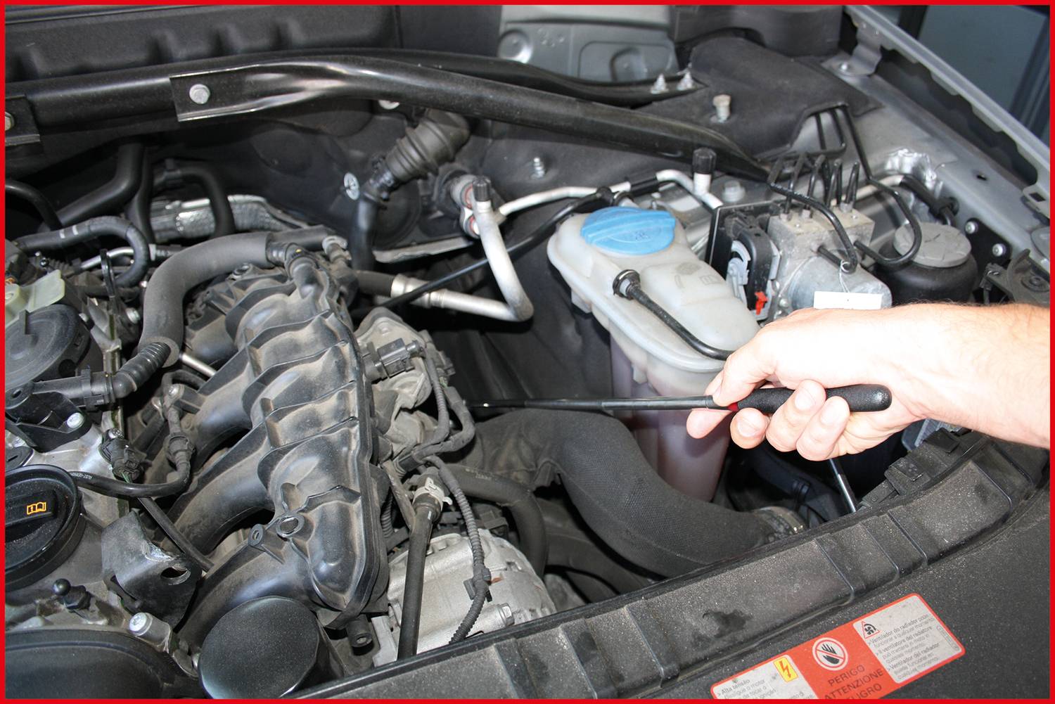 Ruka vyťahuje mierku na meranie oleja z motorového priestoru automobilu, aby skontrolovala jeho hladinu. Motorový priestor zobrazuje rôzne automobilové komponenty.