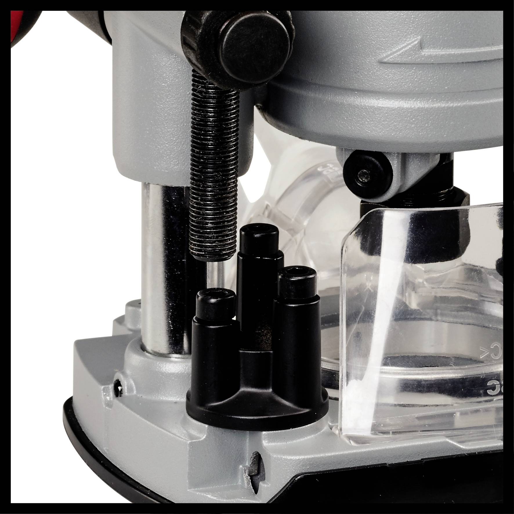 Detailný záber časti stroja, pravdepodobne frézy, s kovovými a priehľadnými komponentmi a čiernymi tlačidlami.