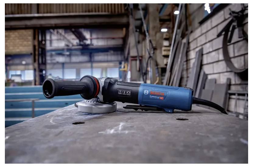 Uhlová brúska na kovovom povrchu v priemyselnom pracovnom priestore, prezentujúca robustnú konštrukciu a ergonomický dizajn.