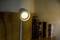 Zapnutá čítacia lampa vrháva teplé svetlo na knižnú polícu v pozadí.