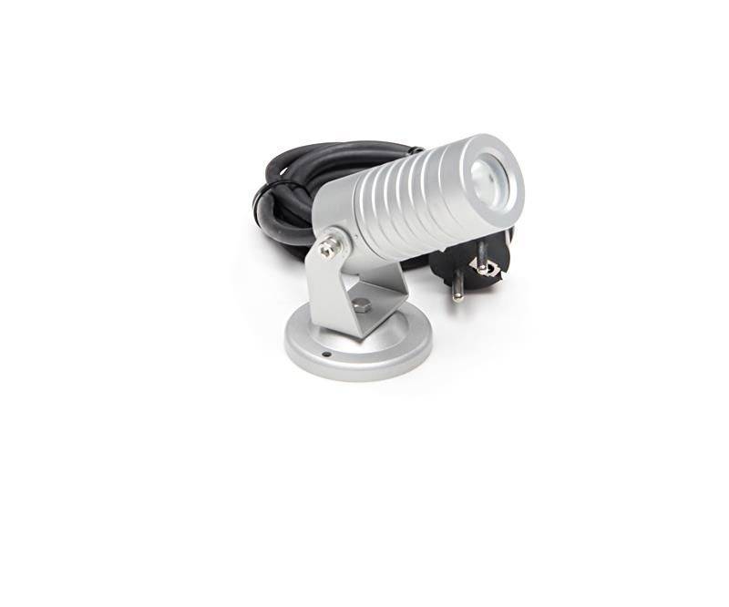 Malý strieborný LED reflektor s čiernym sieťovým káblom a sieťovou zástrčkou, namontovaný na plochej, okrúhlej základni.