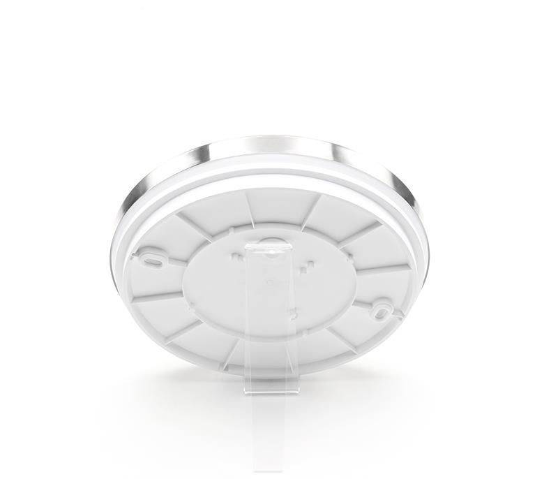 Kruhový, biely uzáver nádoby, pohľadený z jej spodnej strany, vykazuje vyhĺbené a vystúpené štruktúry určené na stabilné upevnenie.