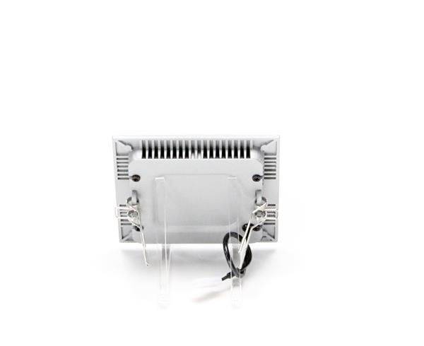 Biela, obdĺžniková lampa so viditeľnými káblami na zadnej strane, umiestnená na priehľadnom podstavci.