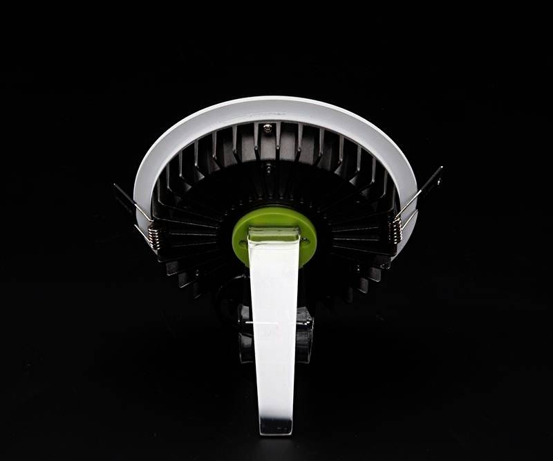 Guľový reproduktor s čiernym chladičom a zelenou stredovou časťou, snímaný zozadu, na čiernom pozadí.