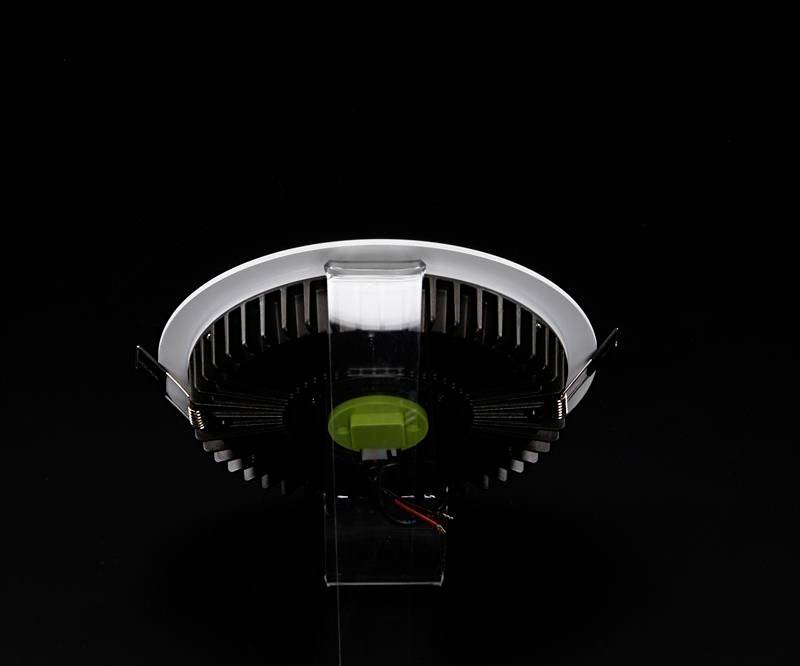 Okrúhle technické zariadenie s čiernym chladičom a bielym prstencom je viditeľné na čiernom pozadí.