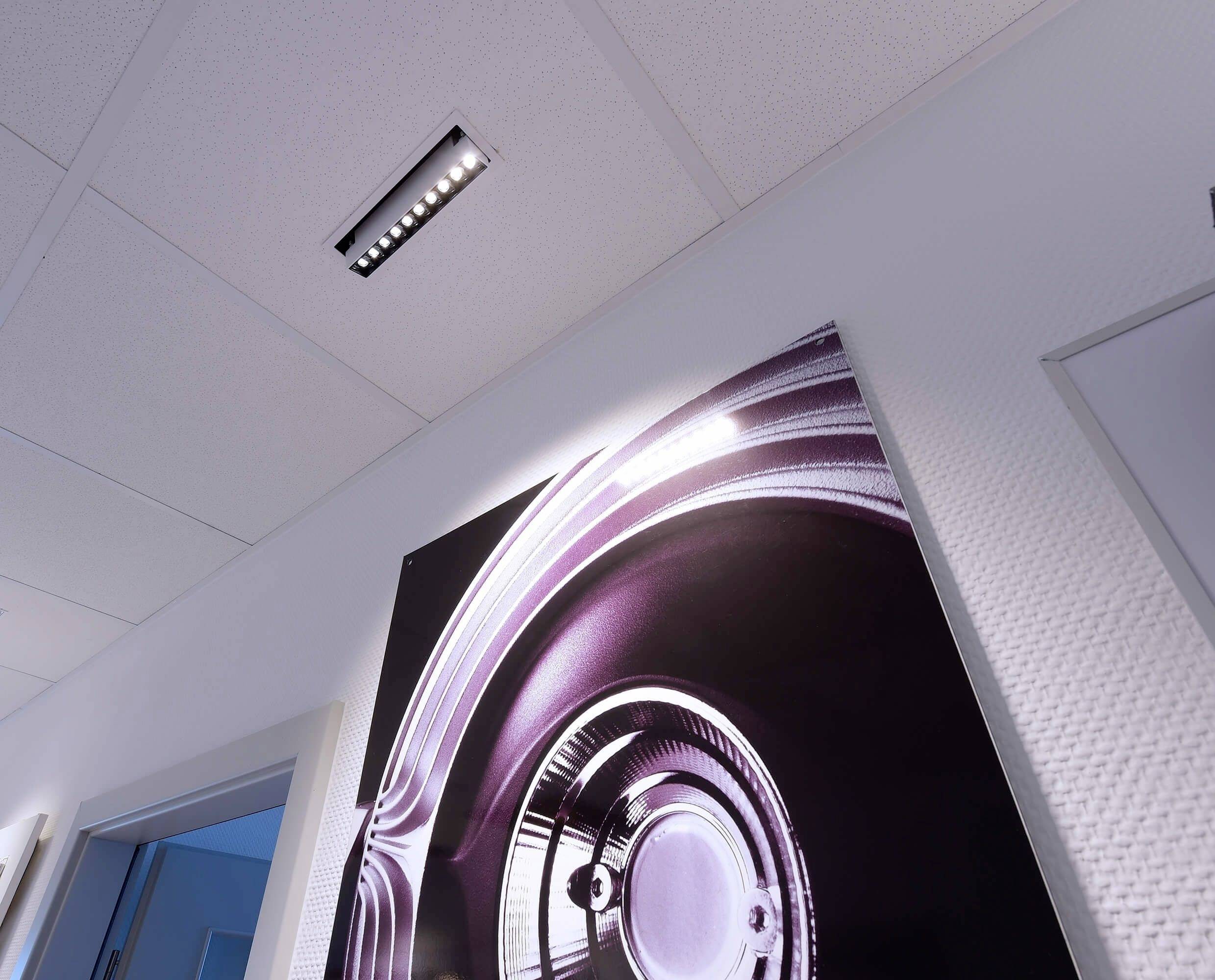 Abstraktné umelecké dielo v odtieňoch fialovej a striebornej visí na stene moderne osvetlenej miestnosti.