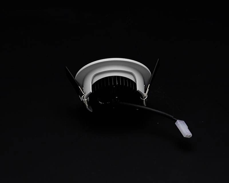 Biela LED stropná zapustená lampa s čiernym chladičom a pripojovacím káblom na čiernom pozadí.