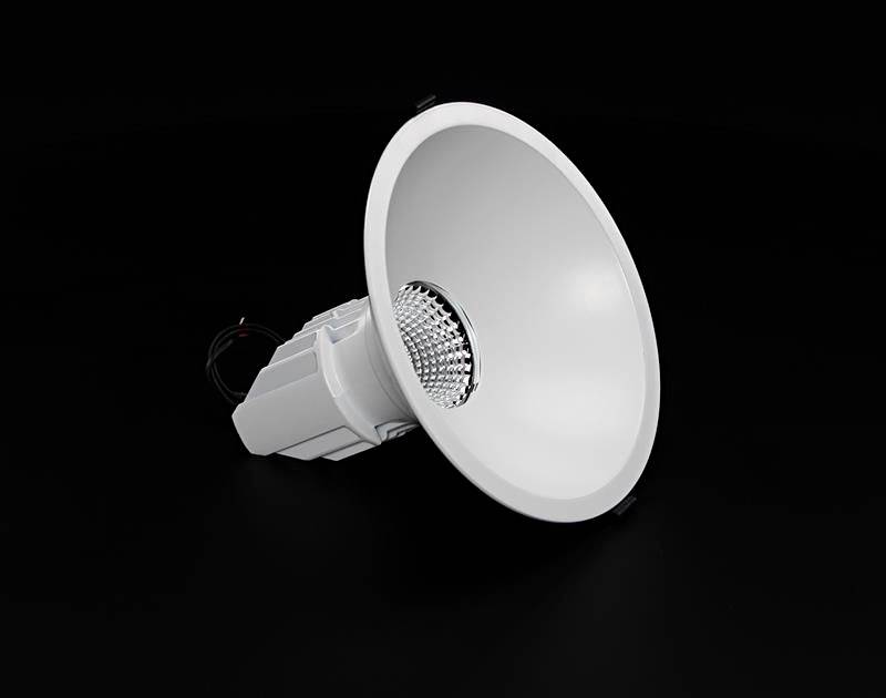 Biely, kruhovitý žiarič na tmavom pozadí, s viditelnými káblami a reflektormi v strede.