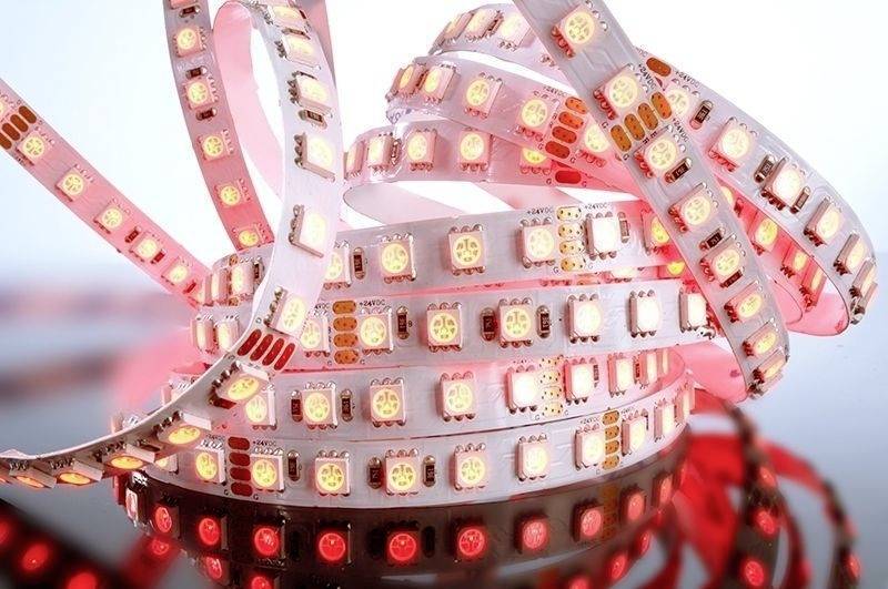 Červené LED svetelné pásy, navinuté a svietiace, pred bielym pozadím. Vhodné pre dekoratívne osvetlenie.