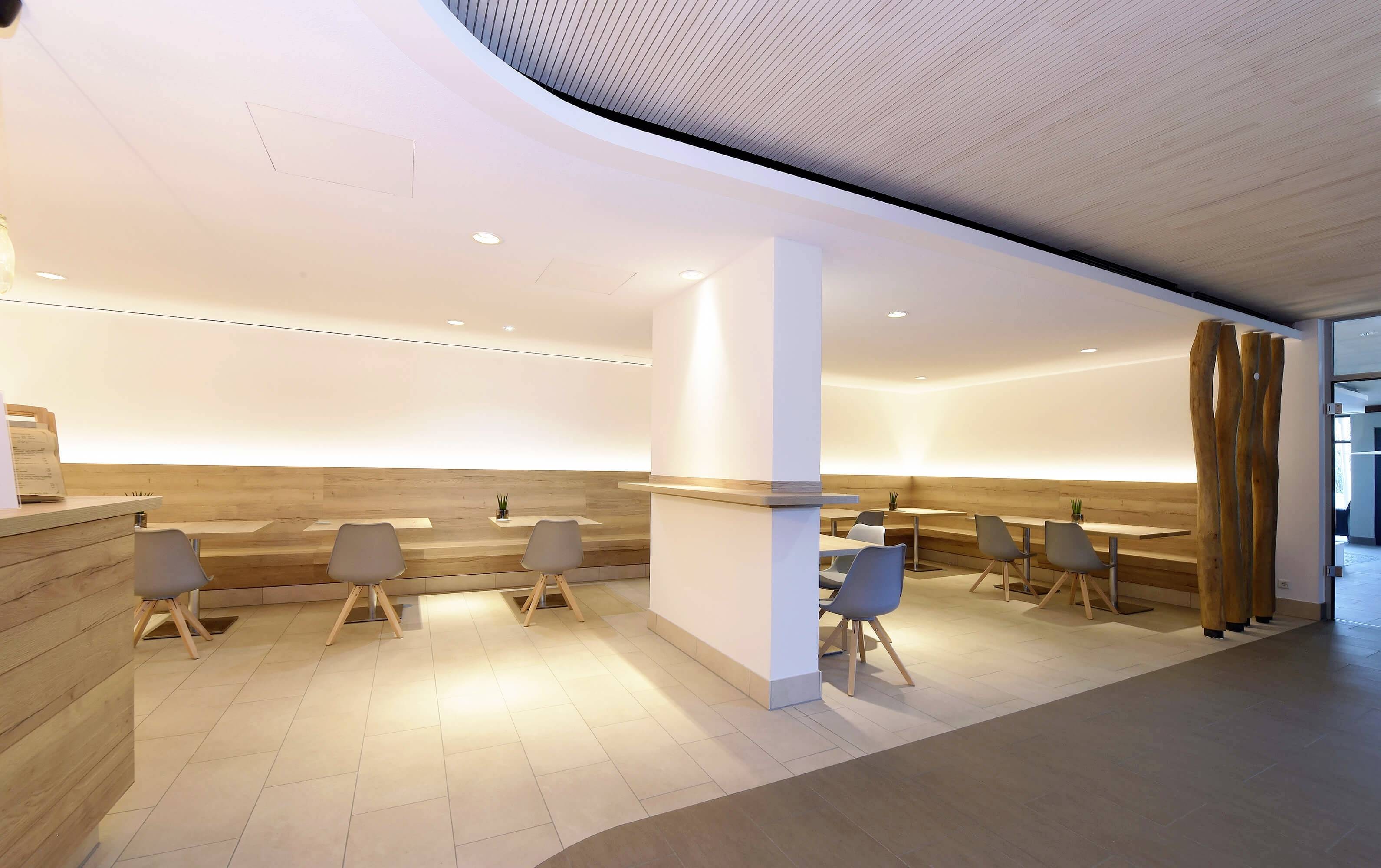 Svetlá jedáleň s nábytkompositým dreveným nábytkom, modernými sivými stoličkami a minimalistickou dekoráciou.