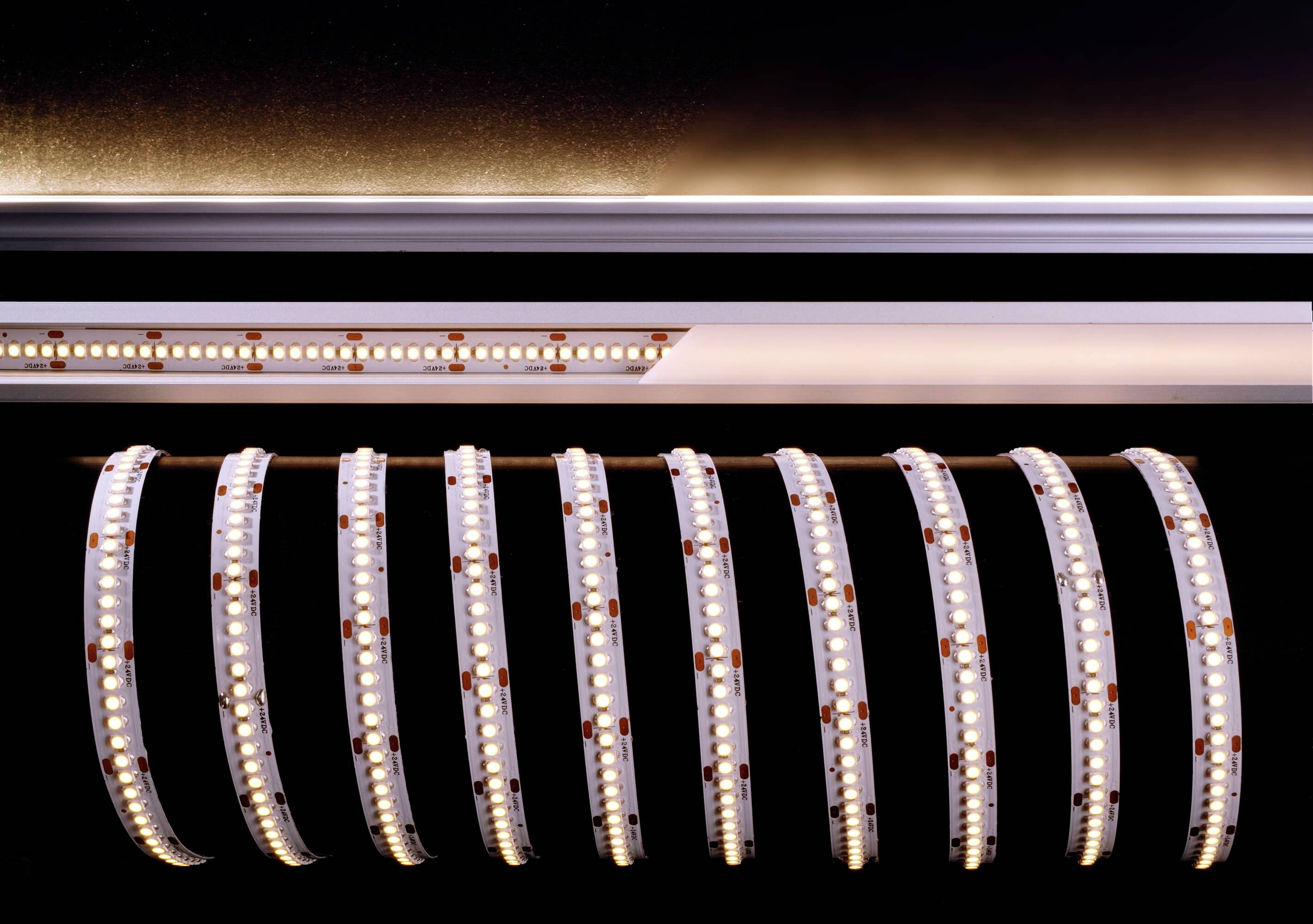 Zvinutá LED svetelná lišta s jasne svietiacimi diódami v tmavej miestnosti. Lišta odhaľuje detaily elektroniky a jej vnútornej štruktúry.