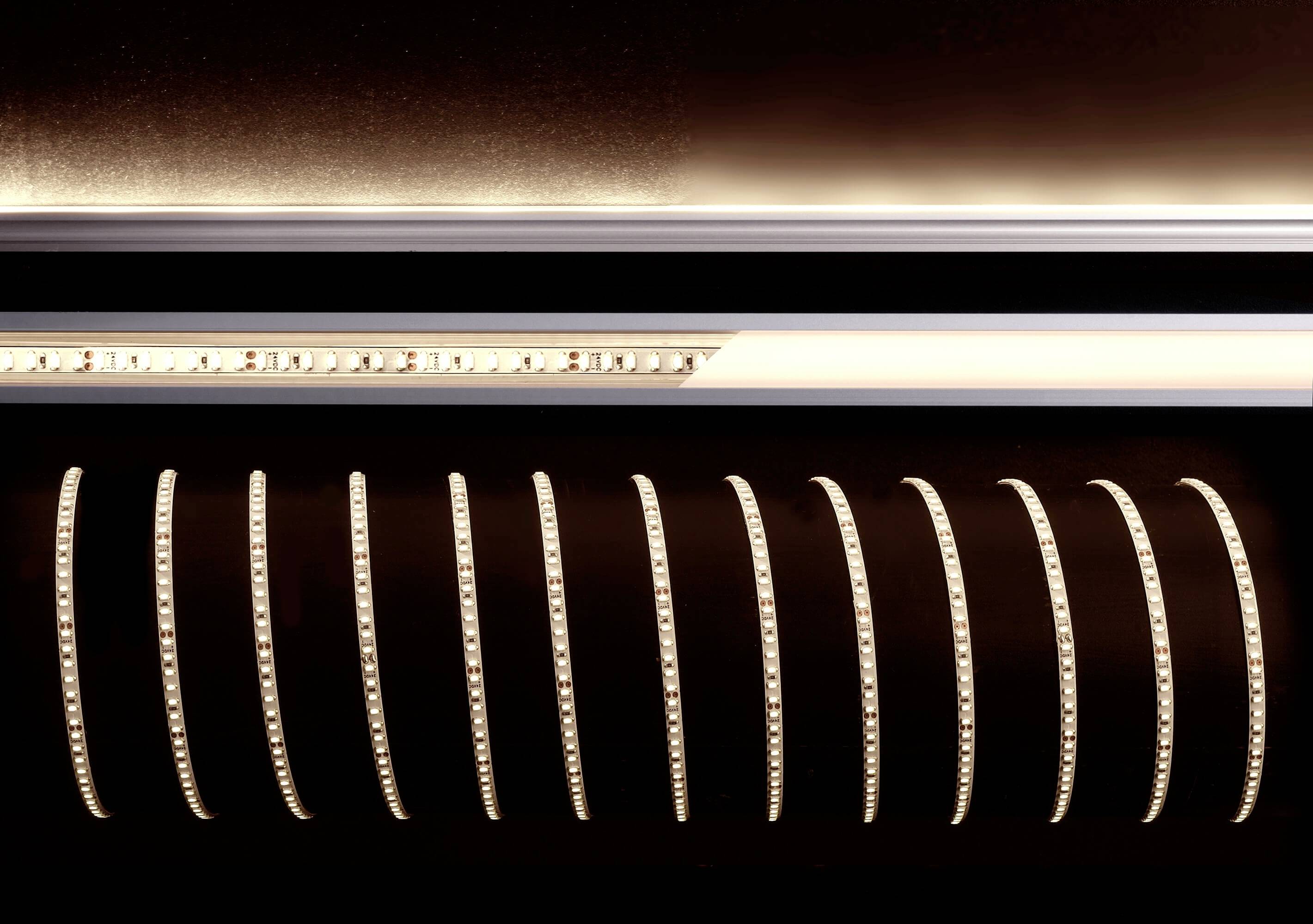 LED pásik v tme, zakrivené usporiadanie, montáž na strop; teplá, žltá farba svetla vytvára jemnú, rovnomernú svetelnú atmosféru.