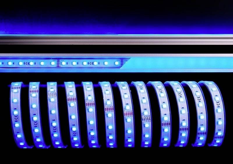 Svetelné pásy s modrým LED svetlom na tmavom pozadí, ktoré prezentujú modernú osvetľovaciu technológiu.