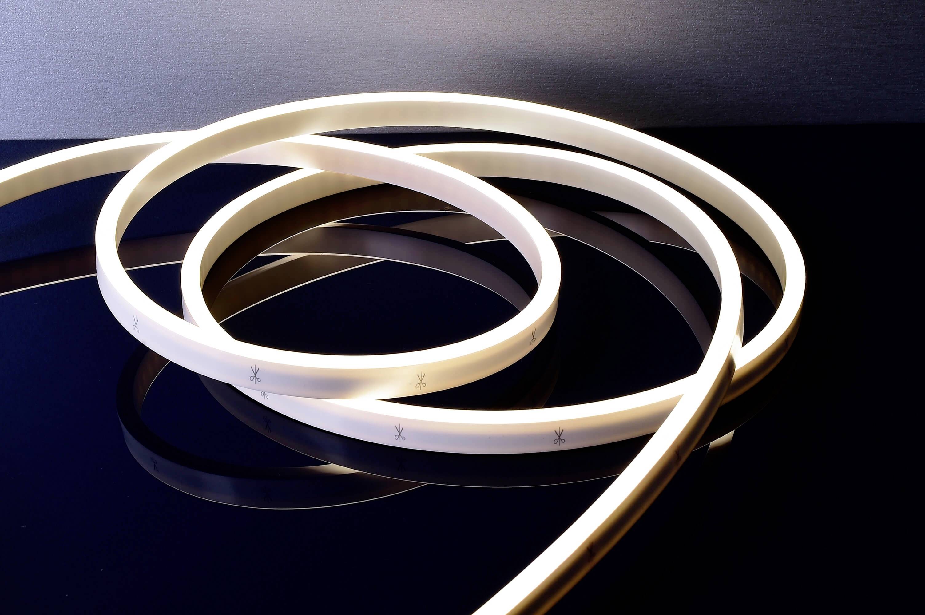 Svetelná LED páska sa vlní po lesklom tmavom povrchu a vytvára odrážajúce efekty.