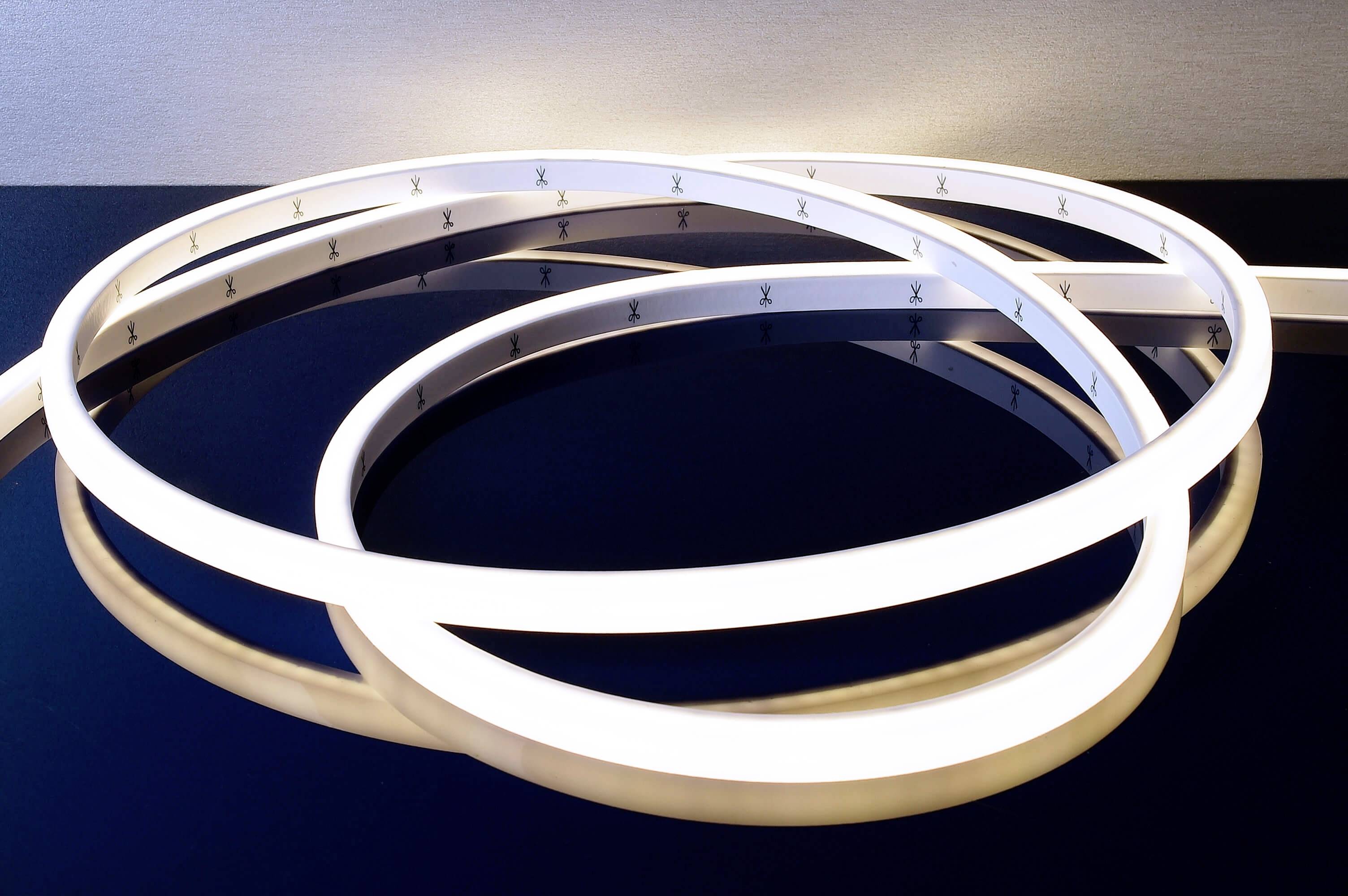 Stočený LED pás na lesklom čiernom povrchu, ktorý vyžaruje jemné, biele svetlo.