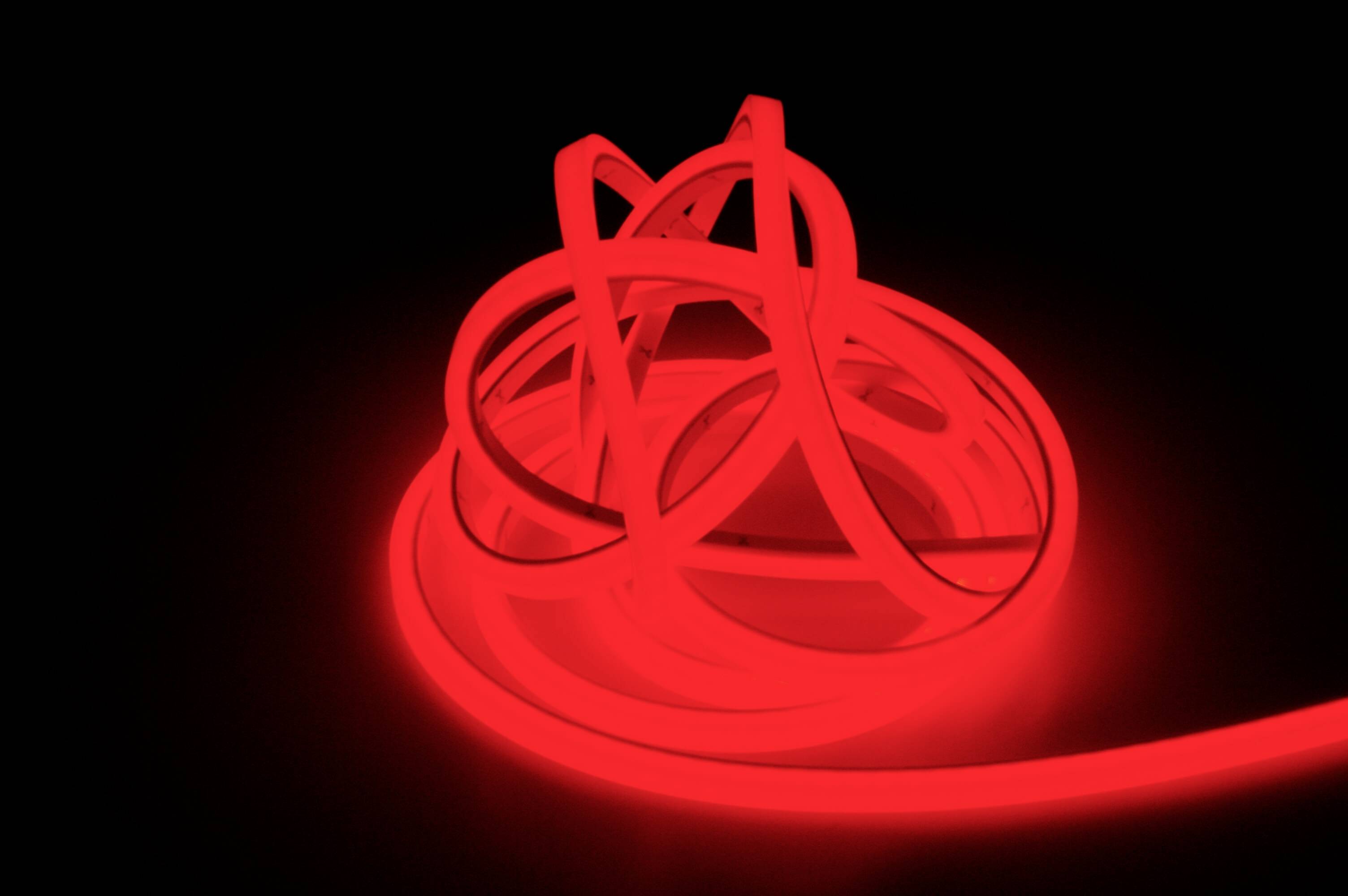 Žiarivá červená LED svetelná slučka leží v záhyboch na tmavom pozadí a vytvára futuristickú atmosféru.