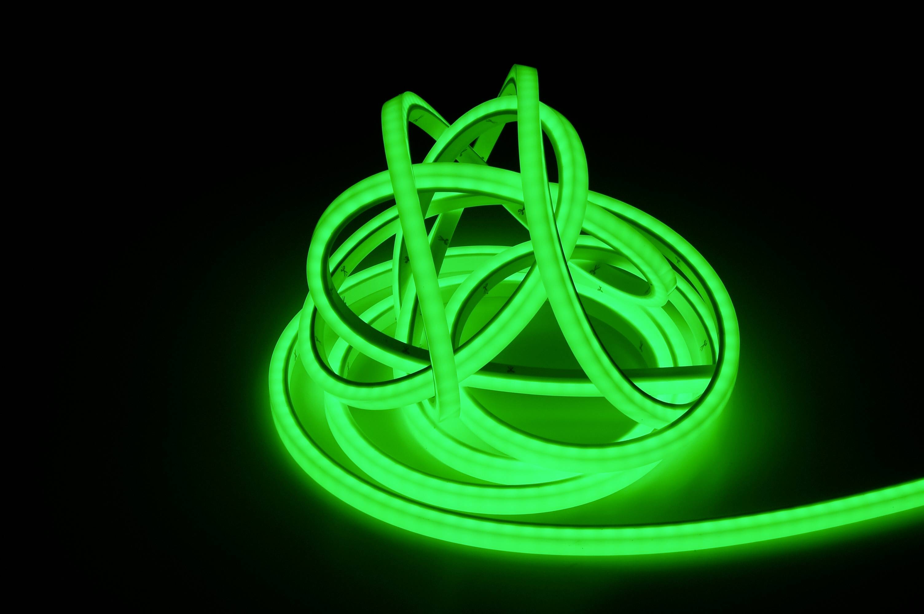 Svetelný zelený LED pás je stočený do komplikovaného vzoru a žiari na tmavom pozadí.