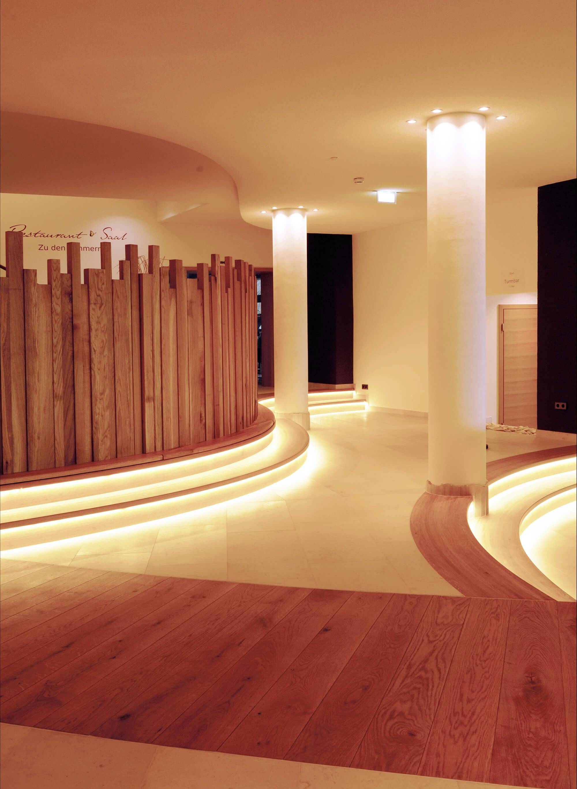 Štýlový, minimalistický priestor s dreveným obložením a oblými svetlami, ktoré vytvára teplú, prívetivú atmosféru.