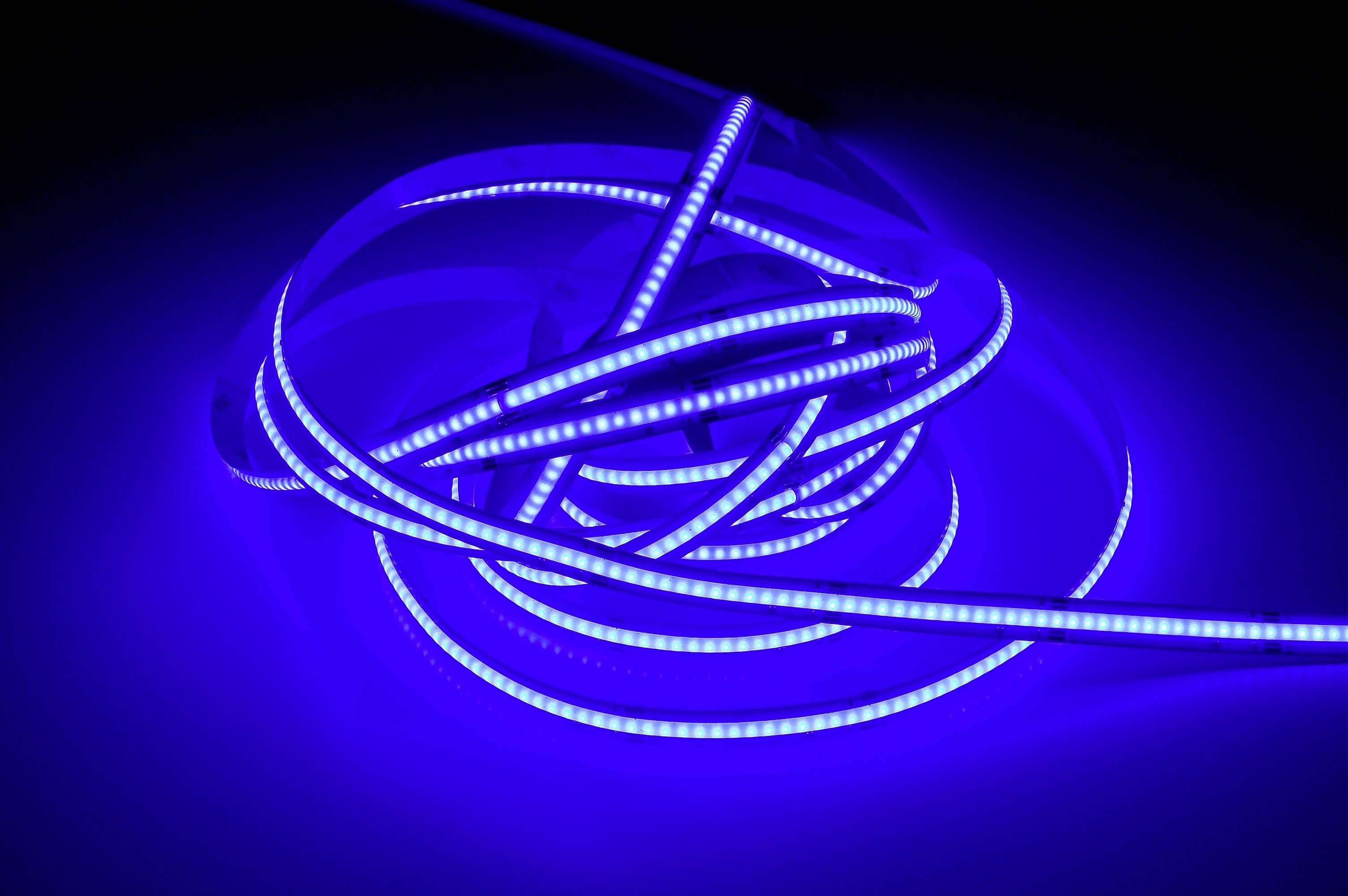 Svetelné modré LED pásy, voľne navinuté na tmavom pozadí, vytvárajú futuristickú atmosféru.