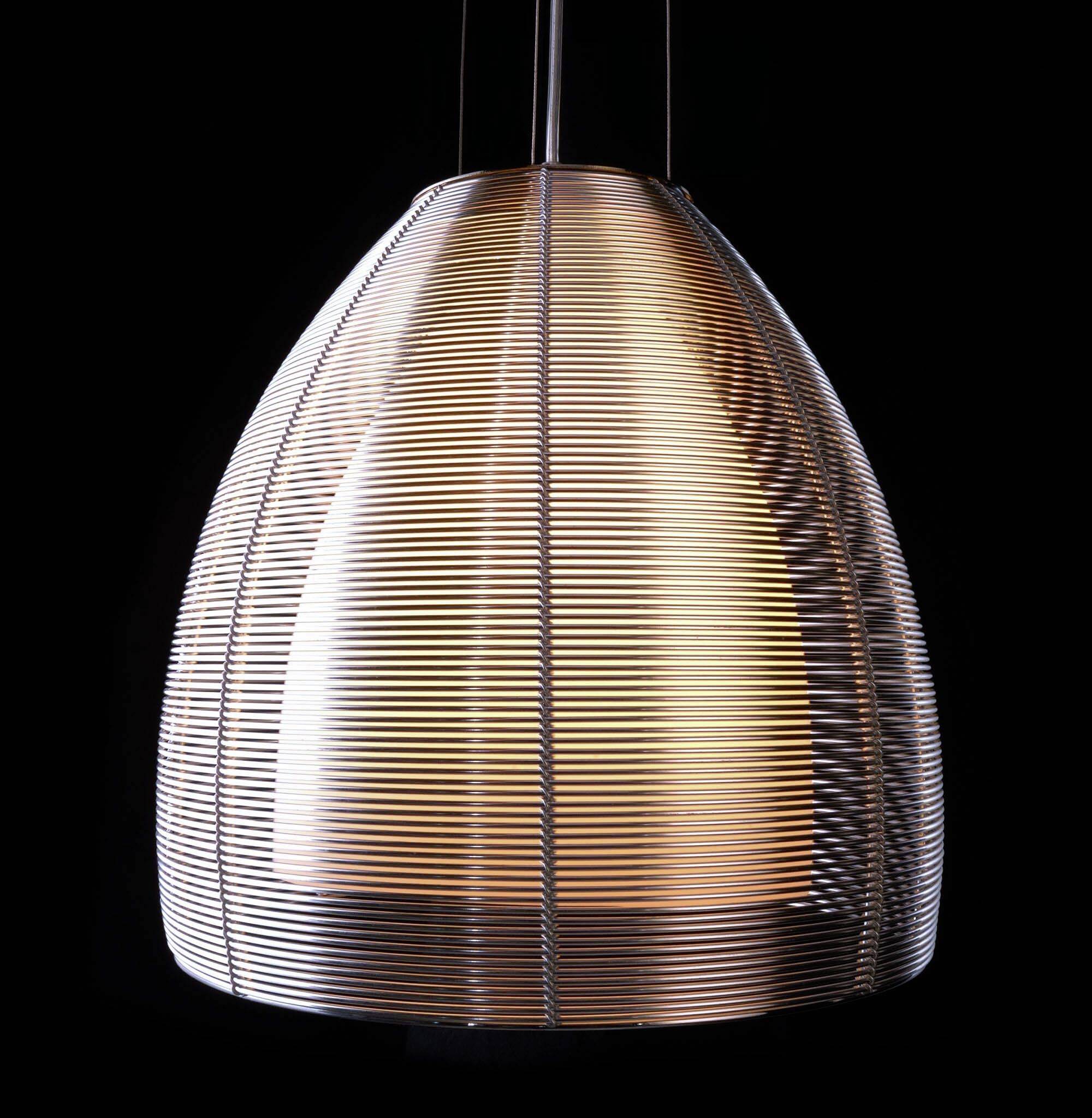 Moderná závesná lampa s tienidlom z priehľadných horizontálnych pruhov. Vo tmavom prostredí žiari teplým svetlom.