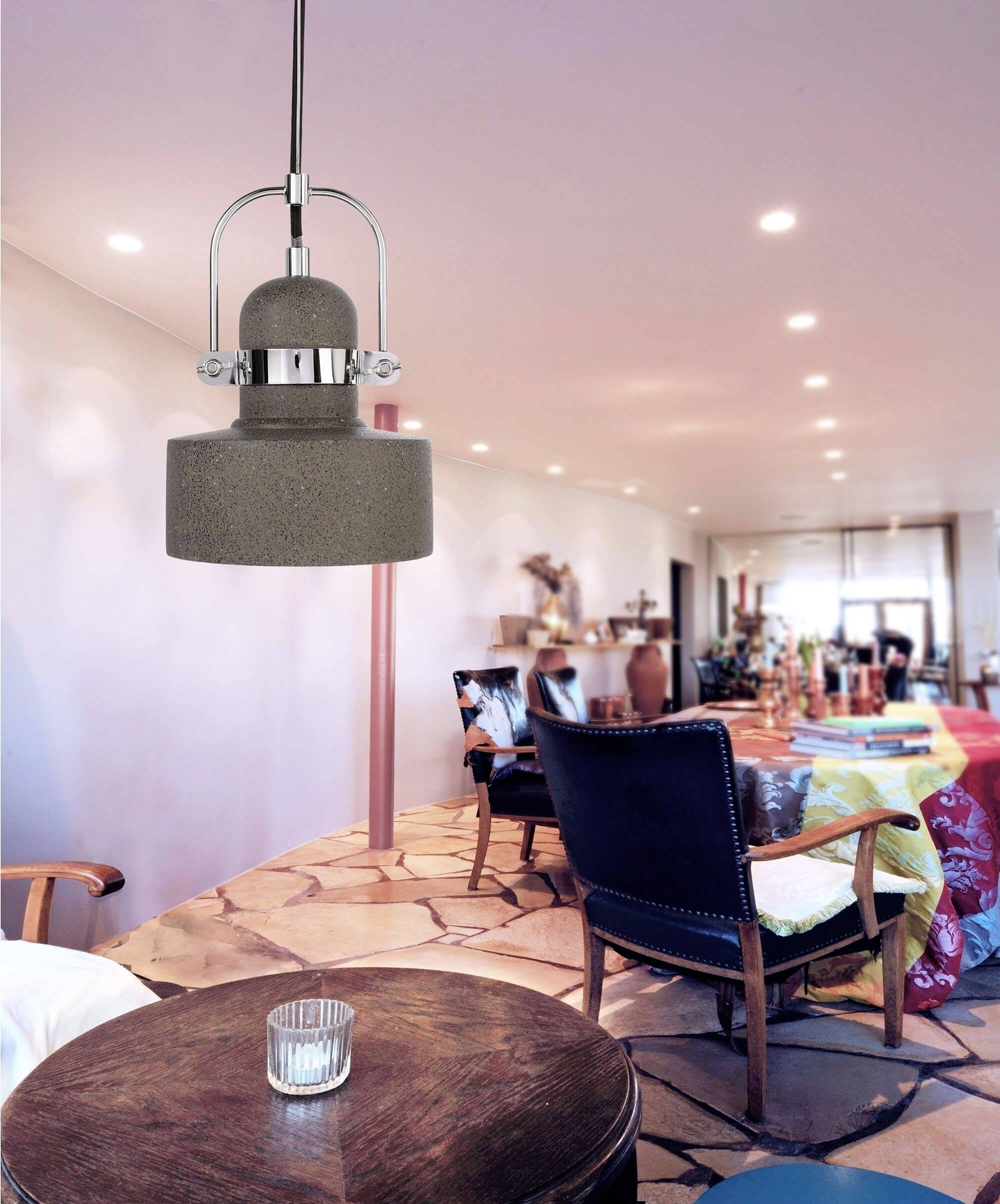 Útulná obývačka s drevenou podlahou. Závesná lampa osvetľuje okrúhly stôl so skleneným predmetom. V pozadí pohovky.