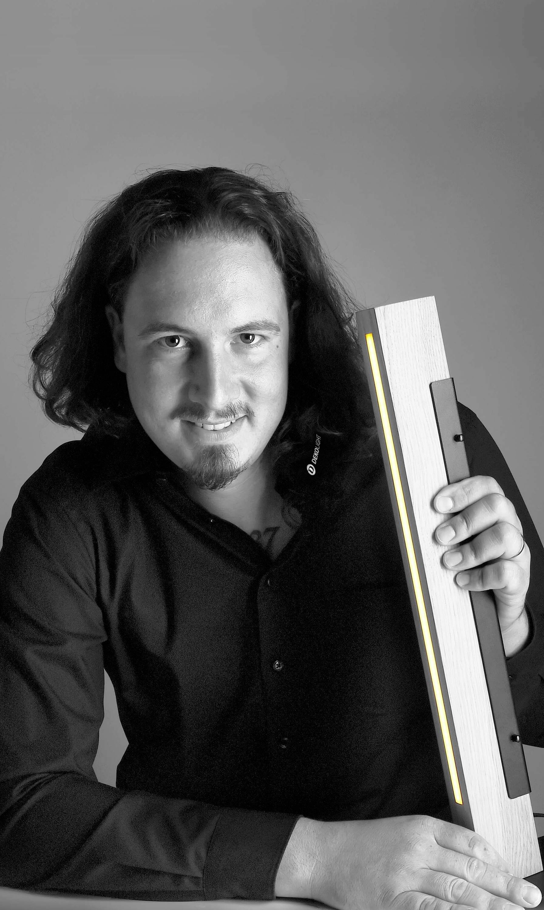 Osoba drží svetelný LED pásik a díva sa do kamery. Scéna je zachytená v čiernobielom prevedení.