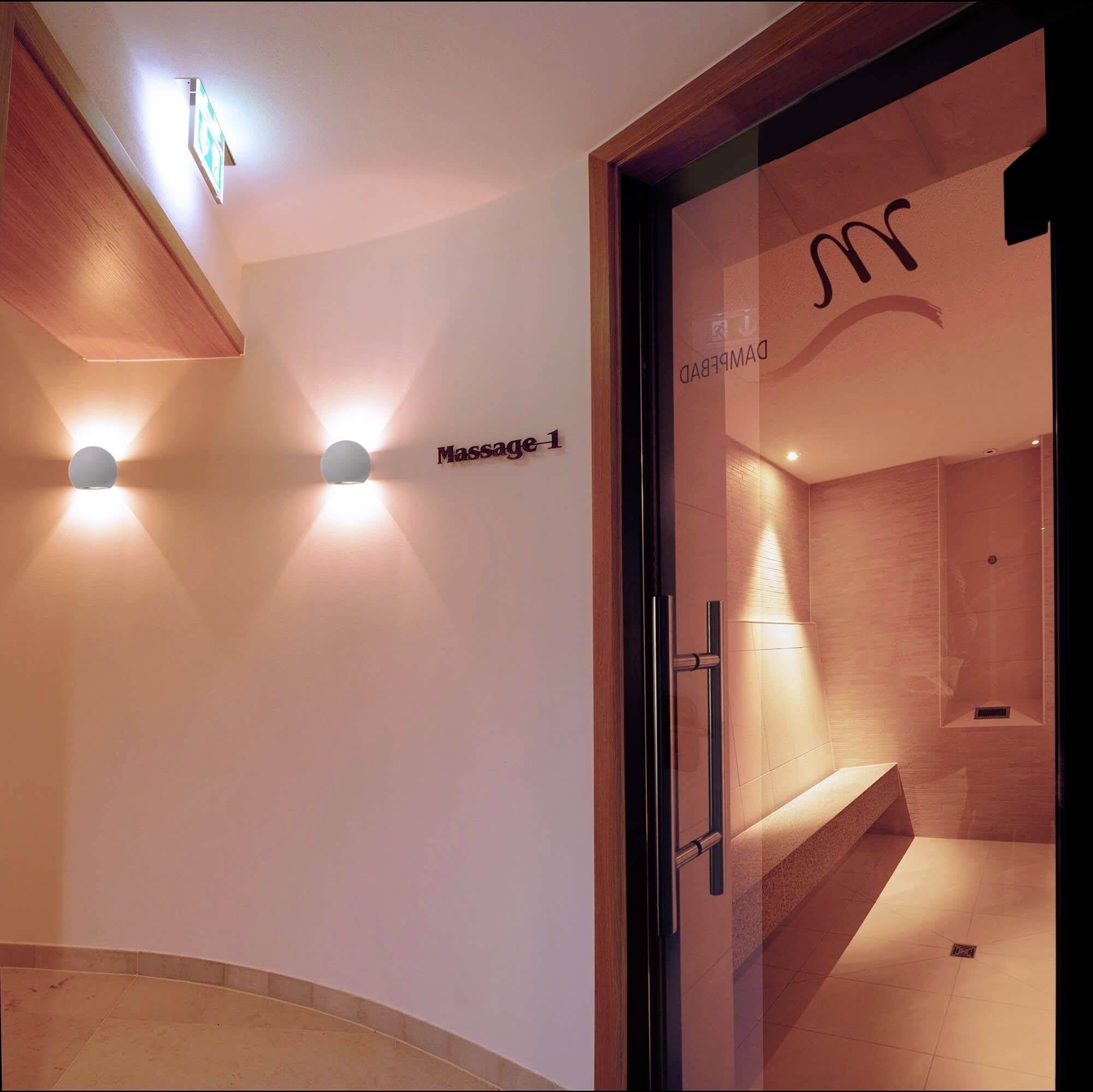 Jemne osvetlená masážna prax s jednoduchou výbavou a tabuľkou na dverách s nápisom 'Masáž 1'.