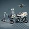 Marsový rover postavený z Lega na rastrovanom povrchu. Malý dronovi podobný lietajúci robot sa vznáša nad ním.