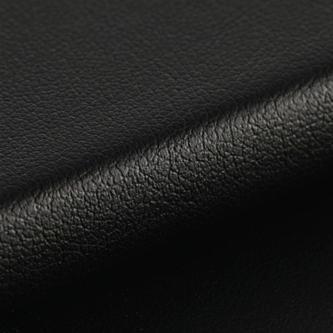 Detailný záber čiernej kože s viditeľnou jemnou štruktúrou povrchu.