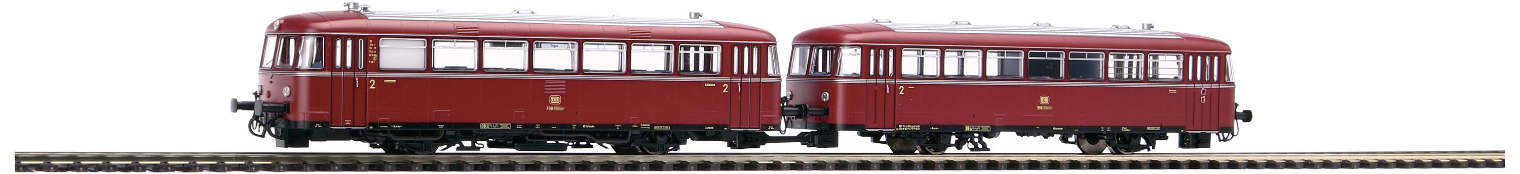 Dva červené modely motorového vozňa na jednej koľaji, v mierke pre modelové železnice.
