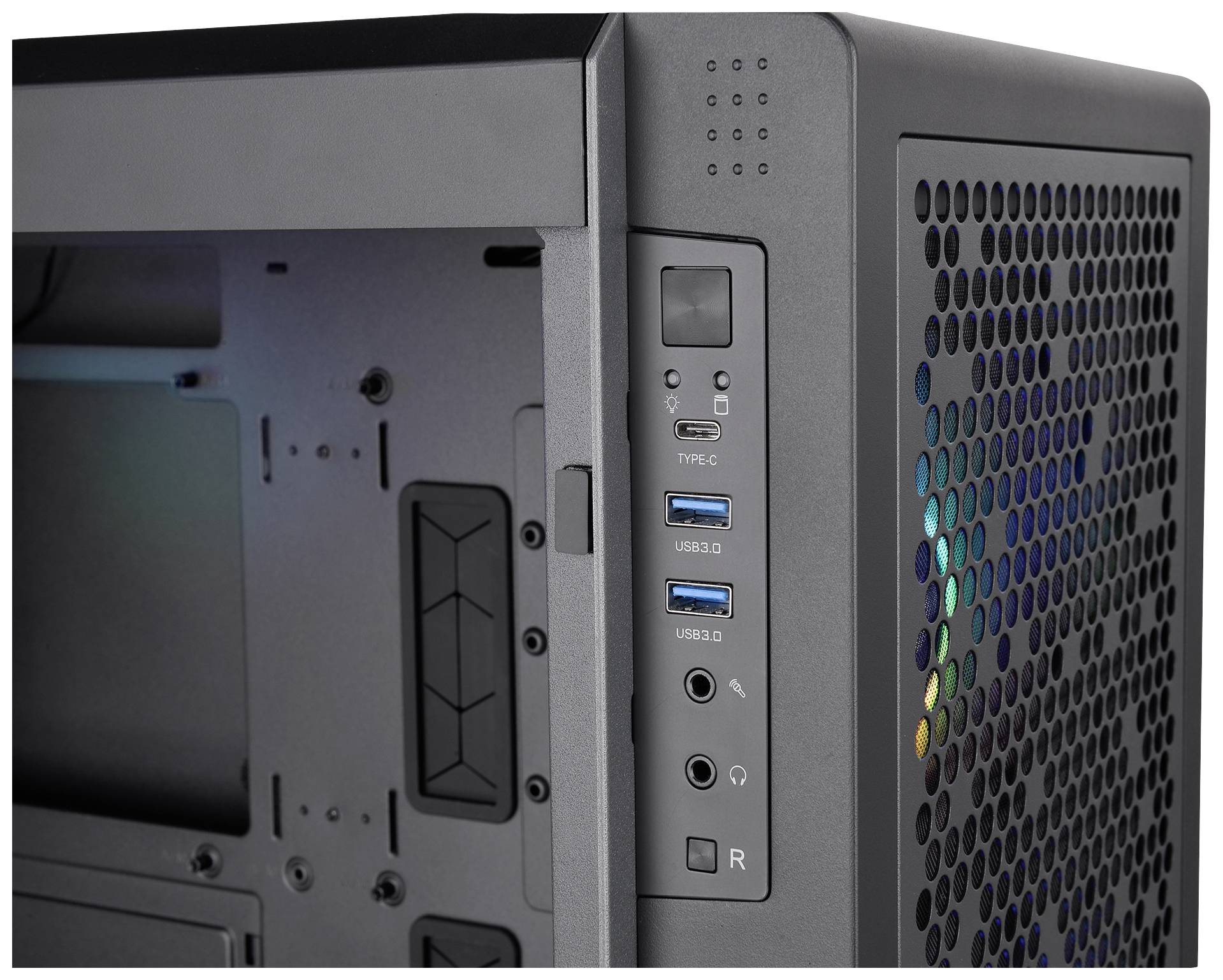 Čierna počítačová skrinka s viacerými USB portami a vetracími otvormi. LED podsvietenie presvitá cez mriežku.