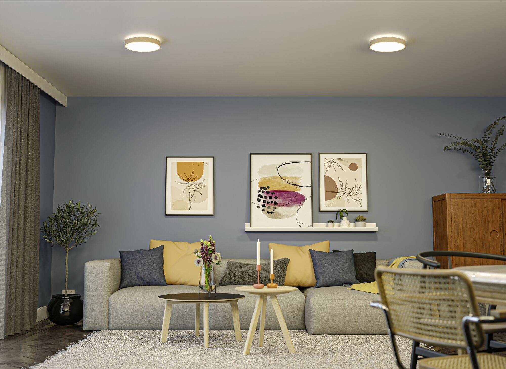 Obývačka so sivou sedačkou, farebnými vankúšmi, malým okrúhlym konferenčným stolíkom, dekoráciami na stene, políčkou s vázami a moderným osvetlením.