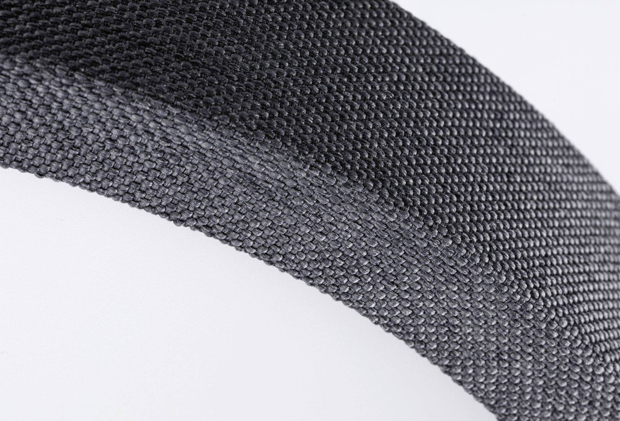 Detailný záber tmavosivého štruktúrovaného materiálu v diagonálnom smere, ktorý odhaľuje vzor povrchu a textúru materiálu.