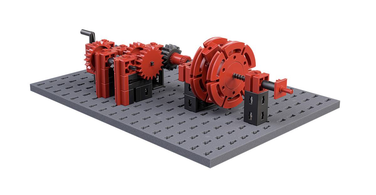 Model s červenými ozubenými kolesami, ktoré sú namontované na šedej základnej doske, zobrazuje rôzne mechanické prepojenia a prevody.