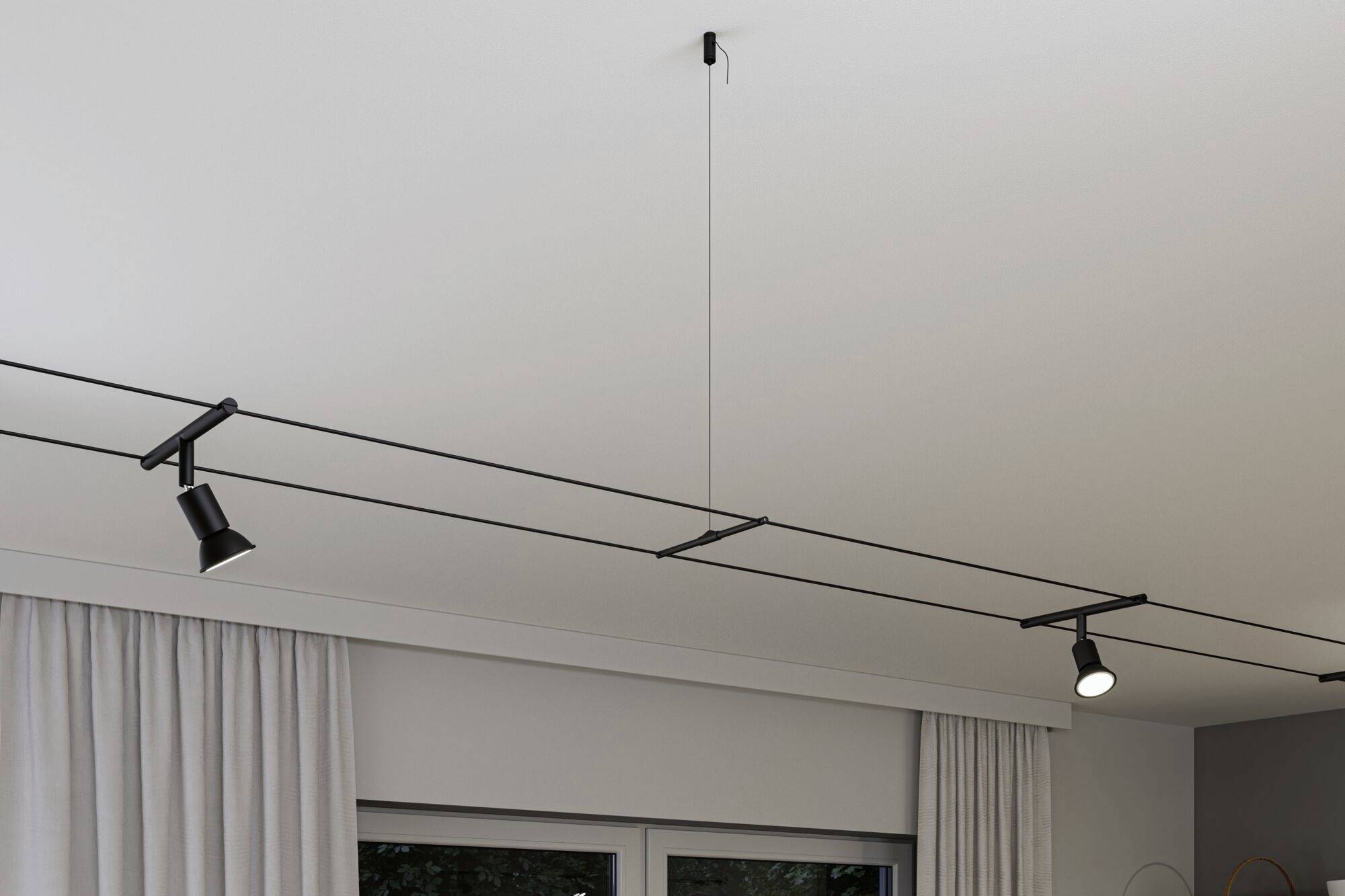Moderné stropné osvetlenie s čiernymi lištami a nastaviteľnými bodovými svetlami nad oknom s bielymi záclonami.