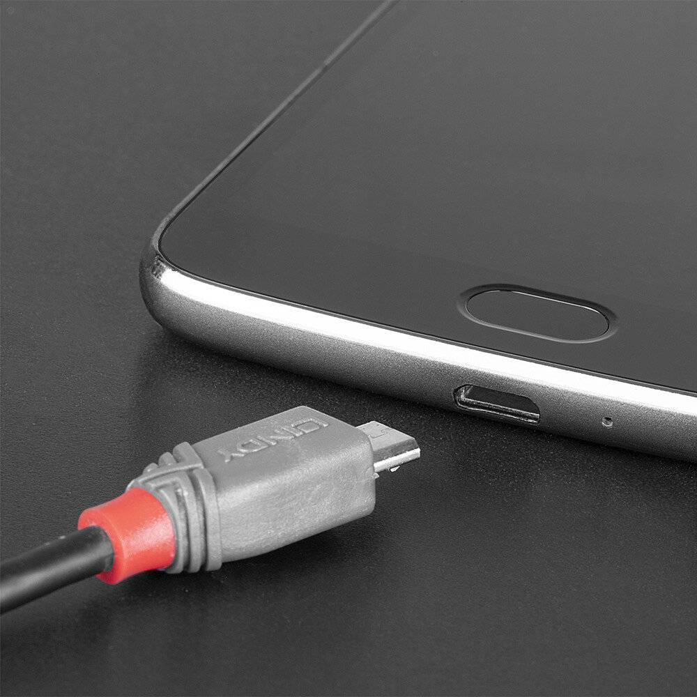 Smartfón leží na stole, vedľa neho je USB kábel. Kábel je pripravený na pripojenie k zariadeniu.