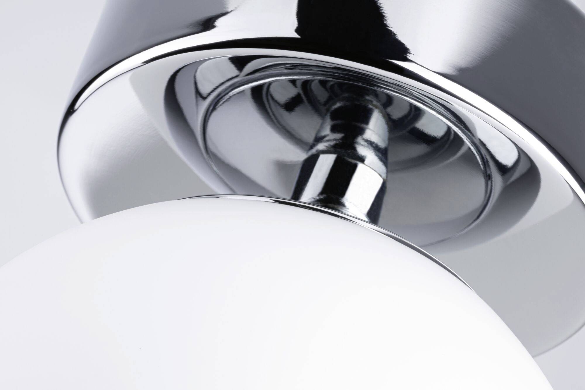 Detailný záber modernej stolnej lampy v chrómovej a bielej farbe s hladkými povrchmi.